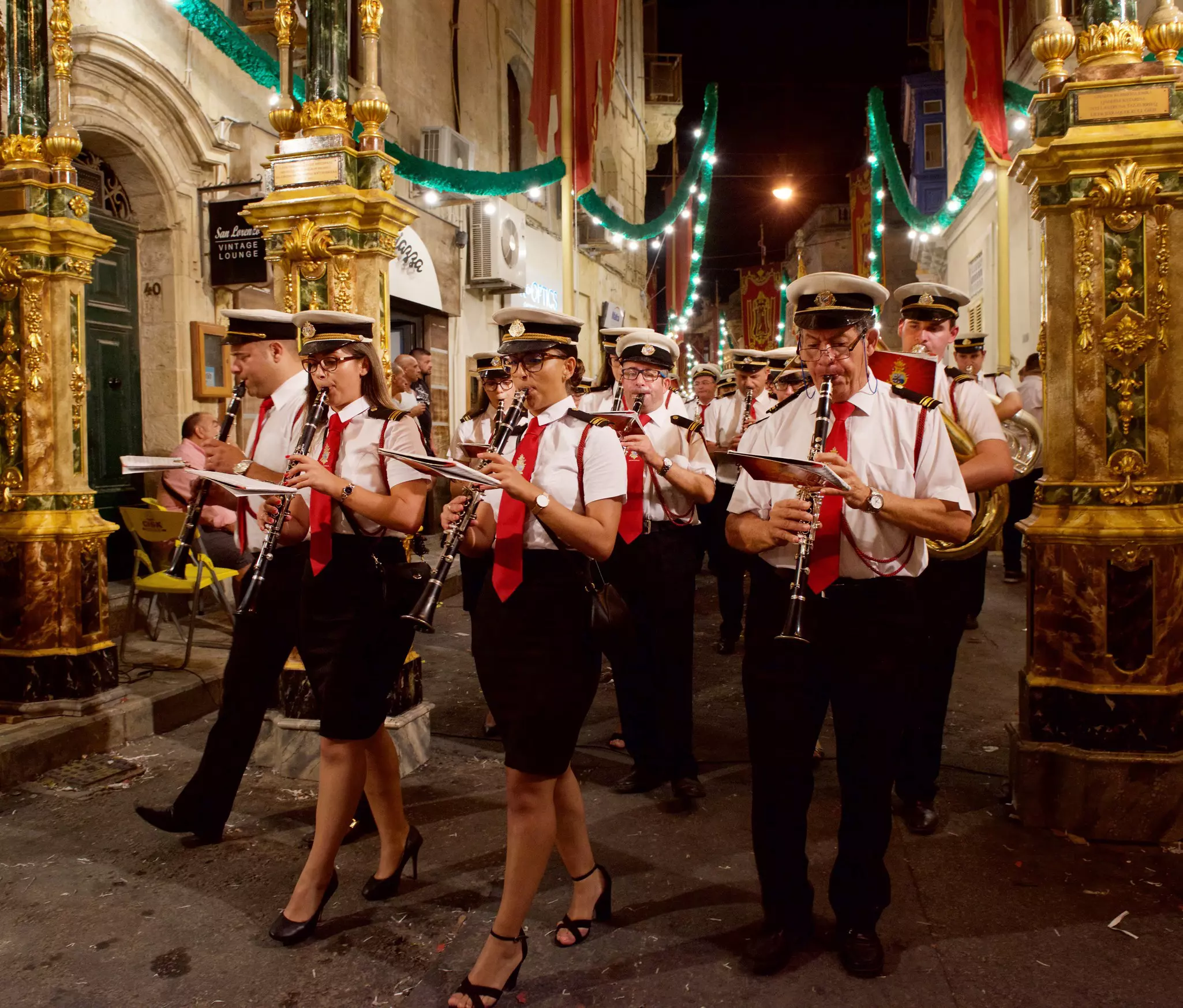 Members of a marching band walk down a street festooned by lights to celebrate the Feast of Santa Catharina in Zurrieq, Malta