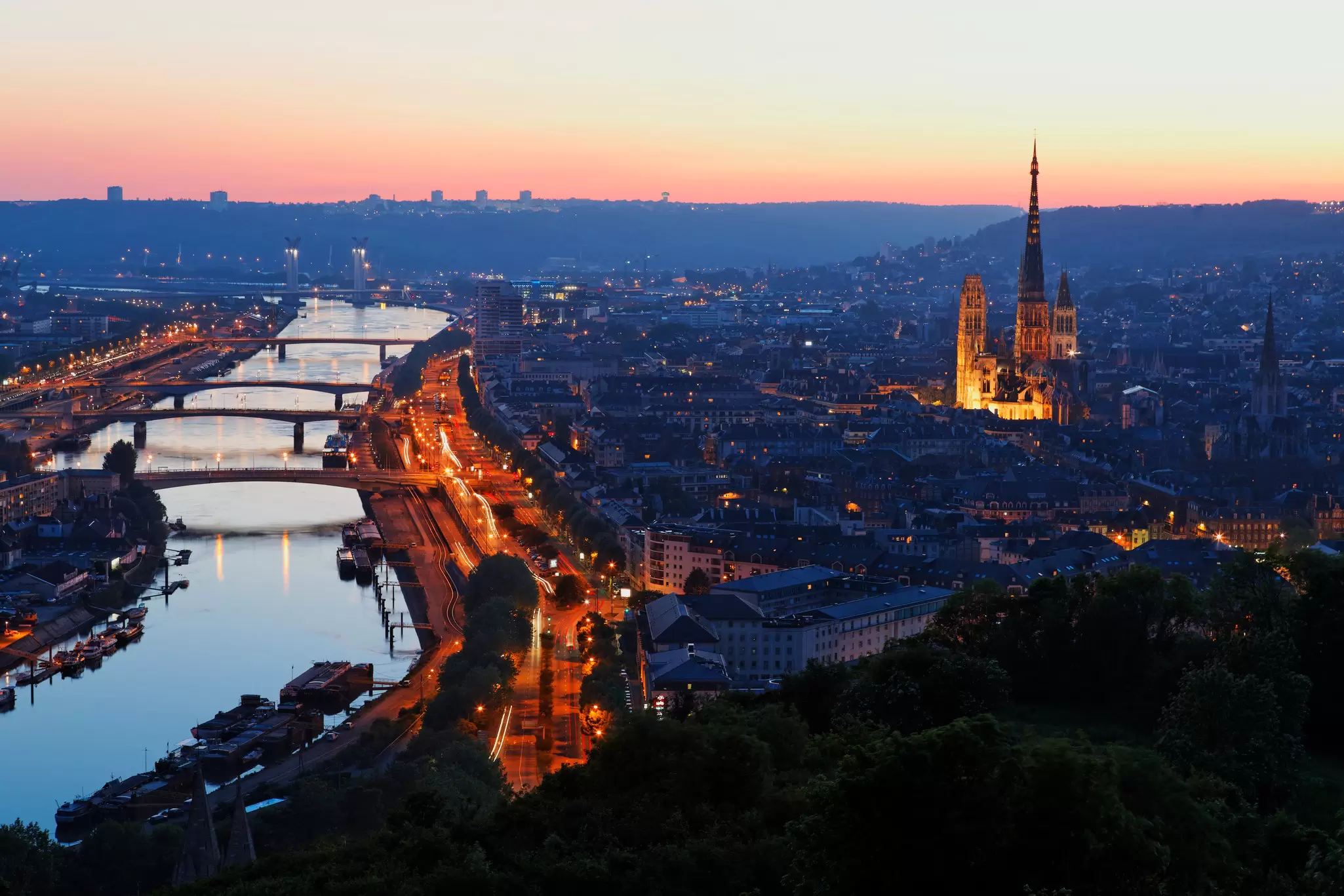 A riverside city at dusk. A large cathdral stands in the centre of the historic part of the city.