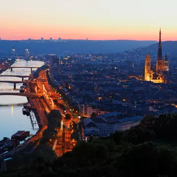 A riverside city at dusk. A large cathdral stands in the centre of the historic part of the city.