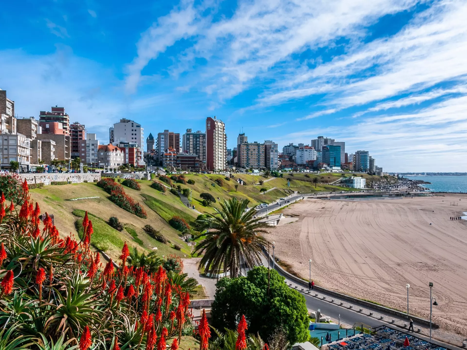 A sandy beach backed by high-rise apartment buildings.
