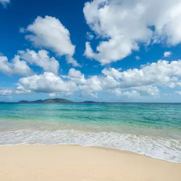 Jost Van Dyke viewed across turquoise Caribbean waters from the white sands of Apple Bay Beach on Tortola, BVI