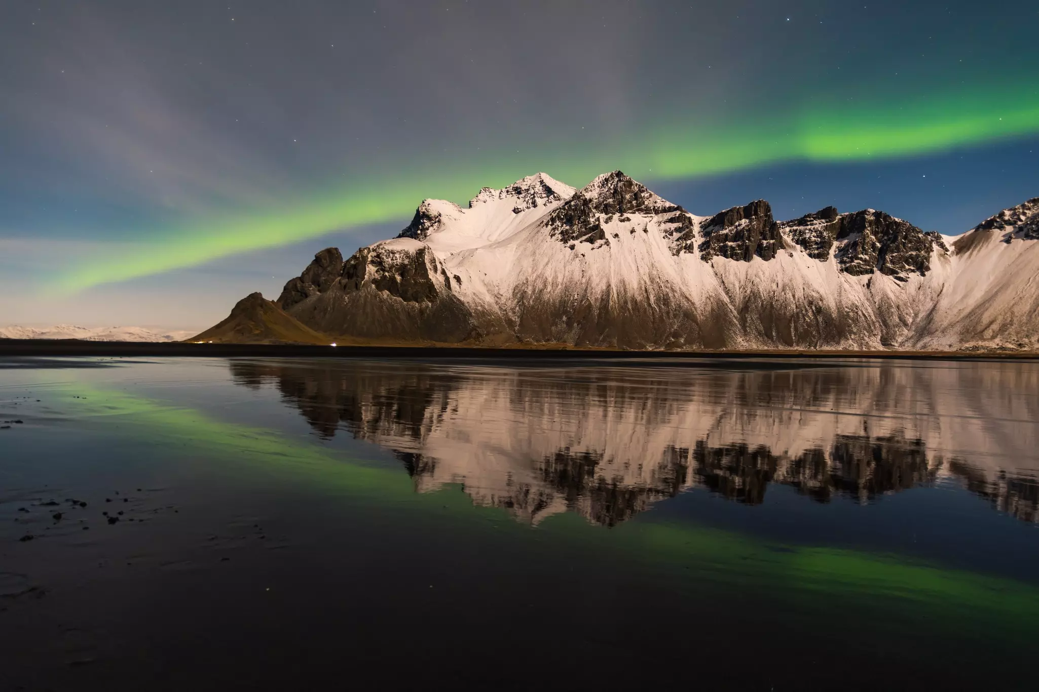 A streak of green light over a jagged mountain.