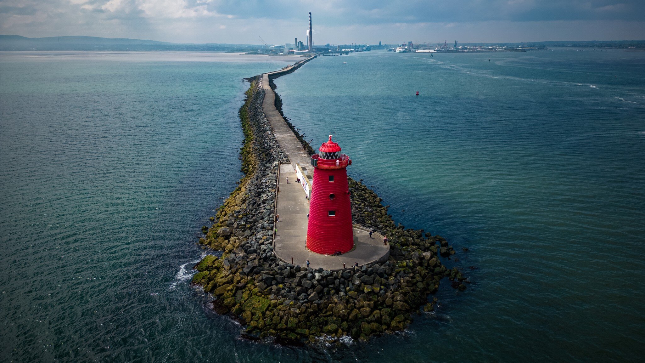 Aerial view of bright red Poolbeg Lighthouse in Dublin coast, Ireland. Skyline far in the background.