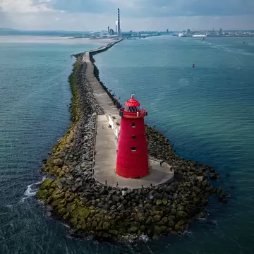 Aerial view of bright red Poolbeg Lighthouse in Dublin coast, Ireland. Skyline far in the background.