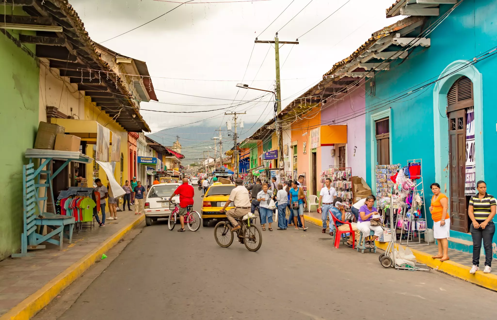 A busy market street lined with pastel-colored low-rise buildings.