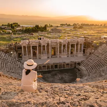 Hierapolis ancient city Pamukkale Turkey, young woman with hat watching sunset by the ruins Unesco ; Shutterstock ID 1167278944; your: Bridget Brown; gl: 65050; netsuite: Online Editorial; full: POI Image Update