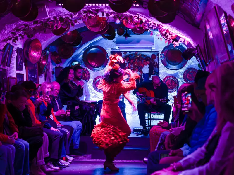 Interior view of a stone house decorated in accordance with the culture of the Albaicin neighborhood and a woman wearing traditional clothing