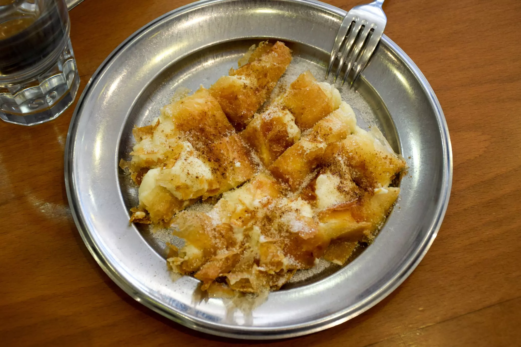 An overhead view of a metal plate piled with a filo-and-cheese pastry.