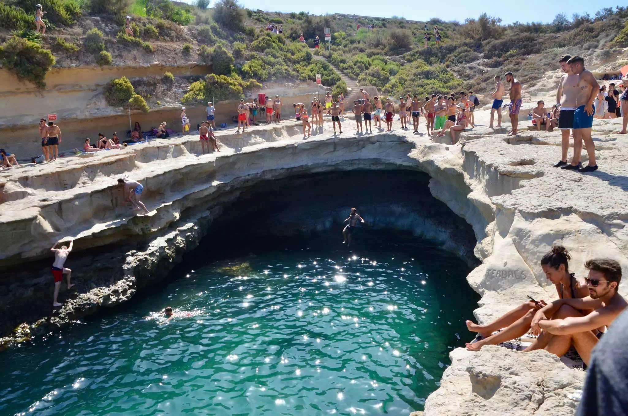 Swimmers and divers sitting around a curved-shape opening to water