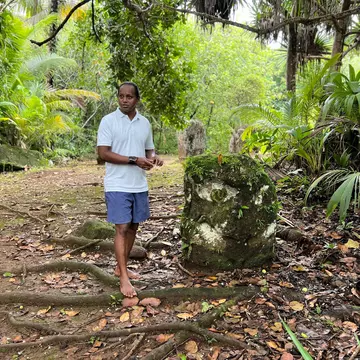 A guide stands beside a stone pillar, one of the Badrulchau monoliths in Palau.