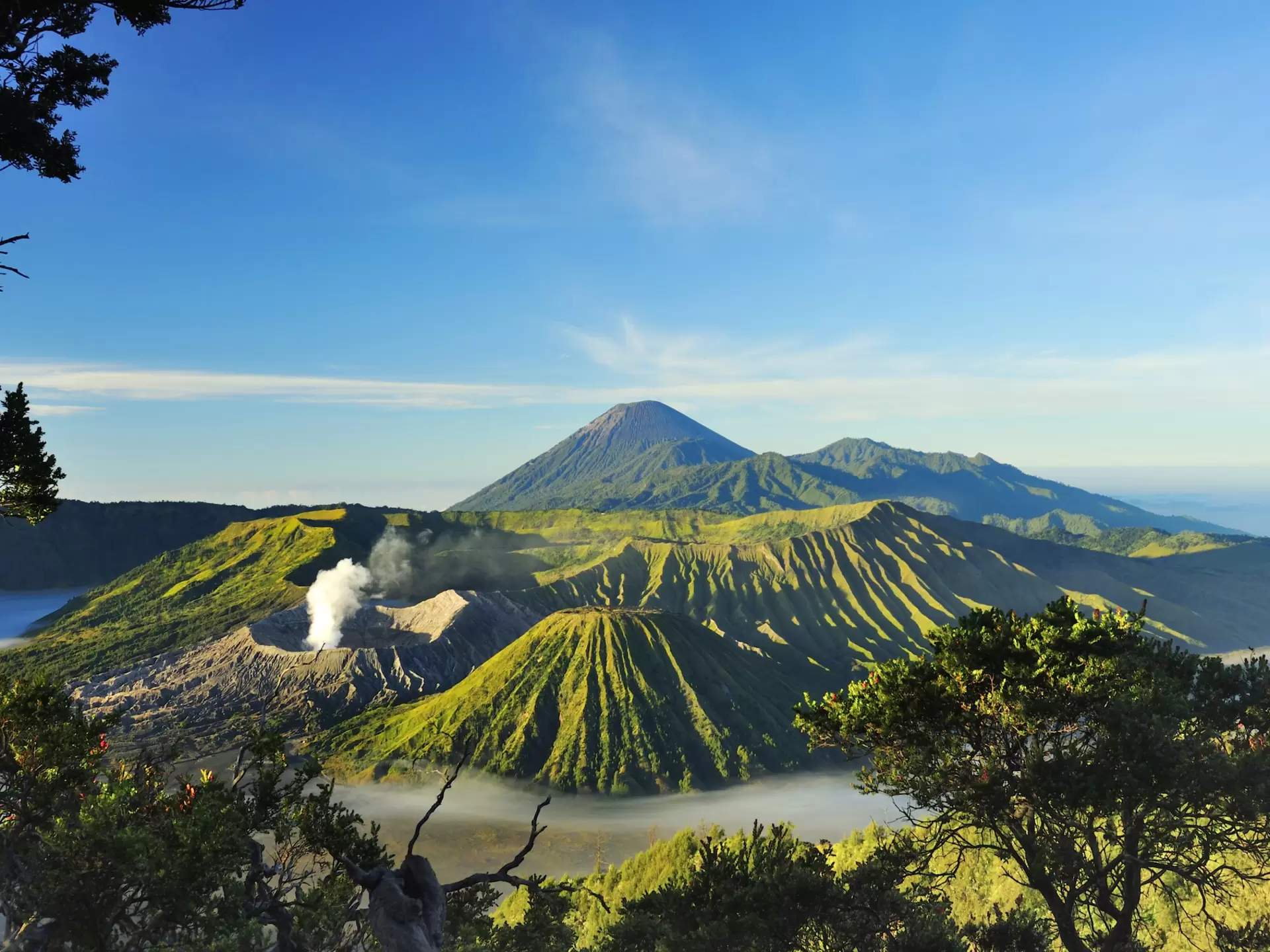 A cluster of volcanoes glowing green in the sunlight, Java, Indonesia