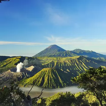 A cluster of volcanoes glowing green in the sunlight, Java, Indonesia