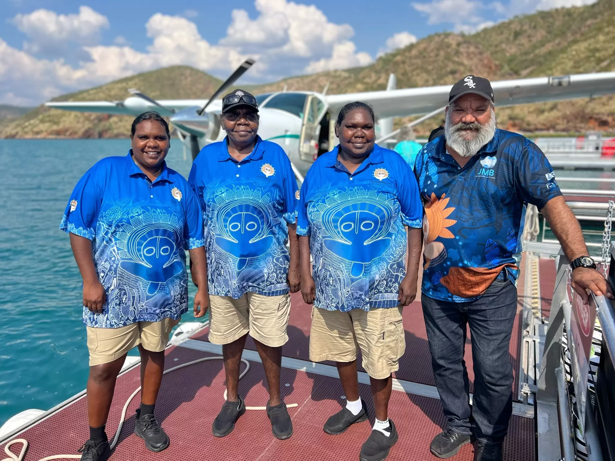Four Aboriginal tour guides pose in front of a seaplane.