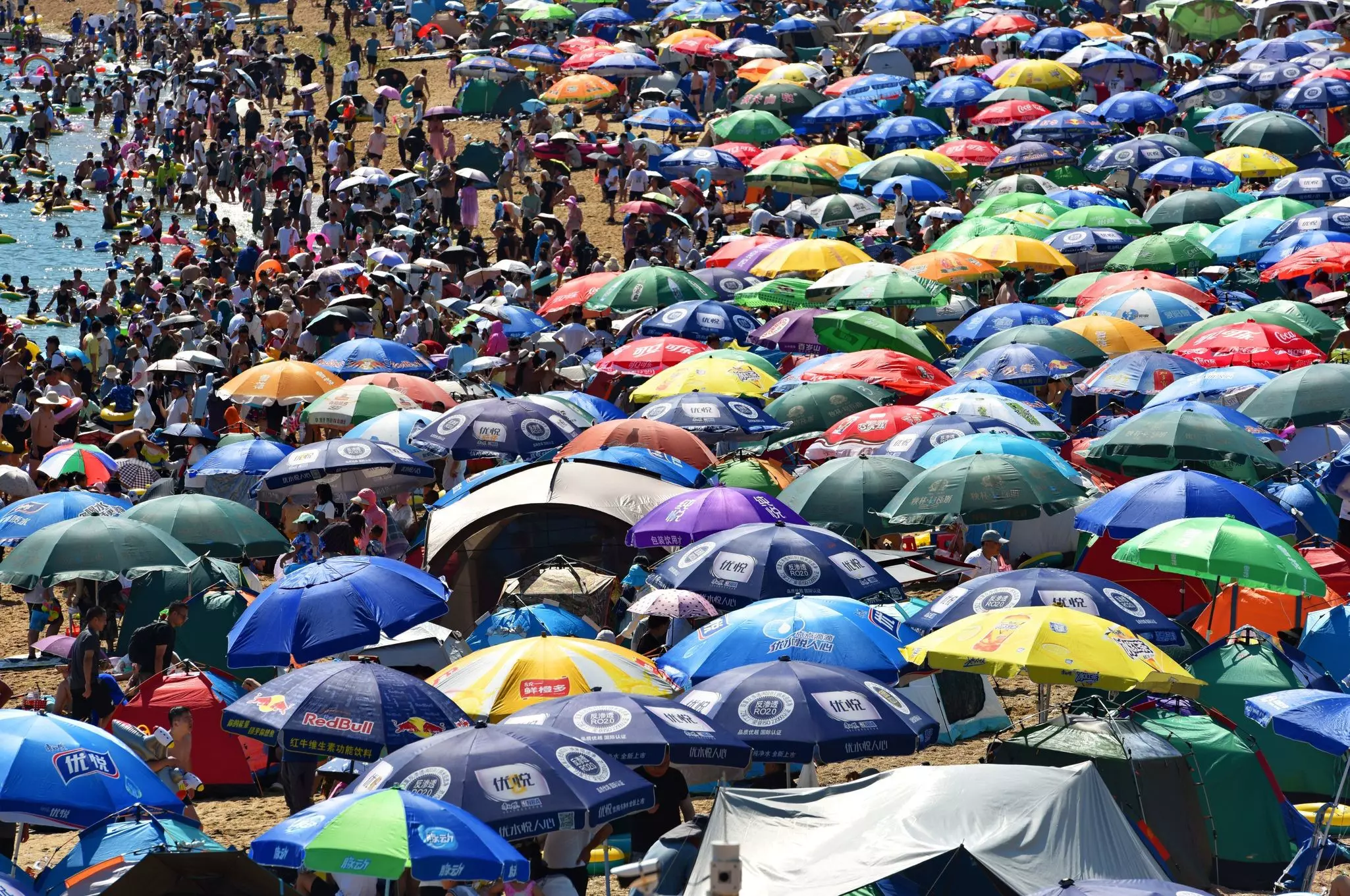 Tourists cluster on a beach to cool off from the heat in Dalian, China © Wang Xizeng / VCG /Getty Images