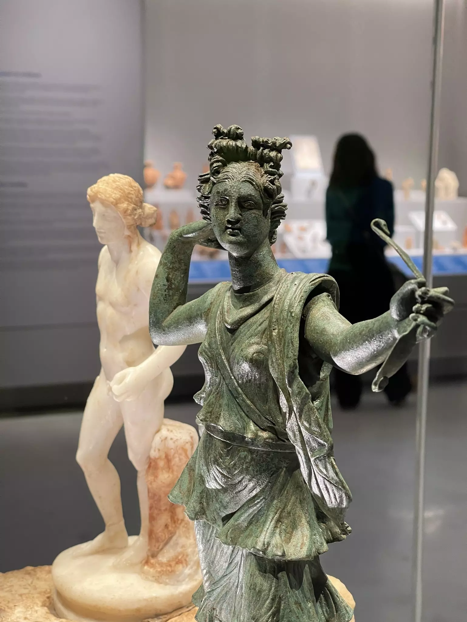 Two sculptures – one in bronze, one in white marble – depicting ancient gods are on display in a museum.