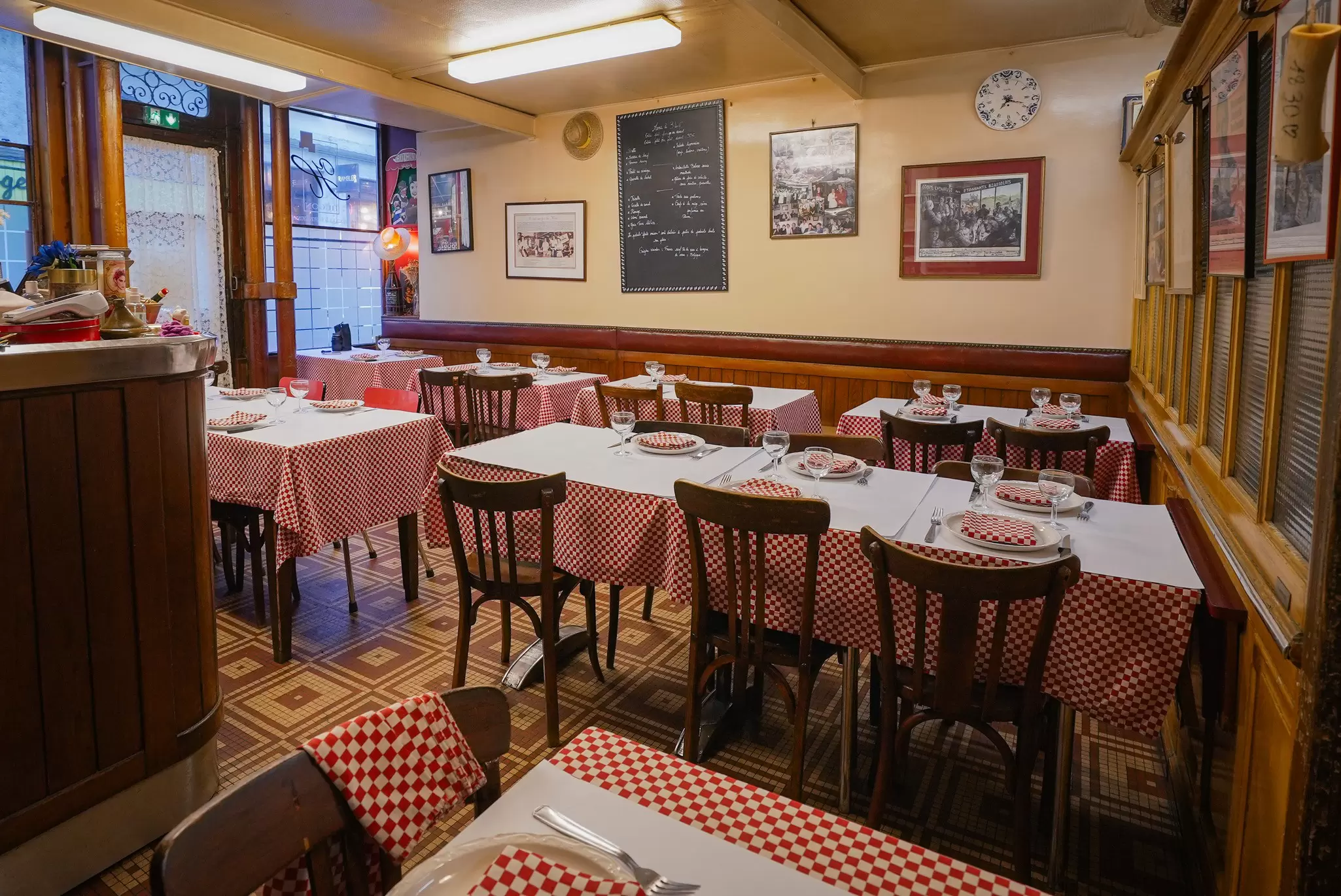 A small bistro with red-and-white checkered table cloths and a menu written in chalk on a blackboard mounted on the wall.