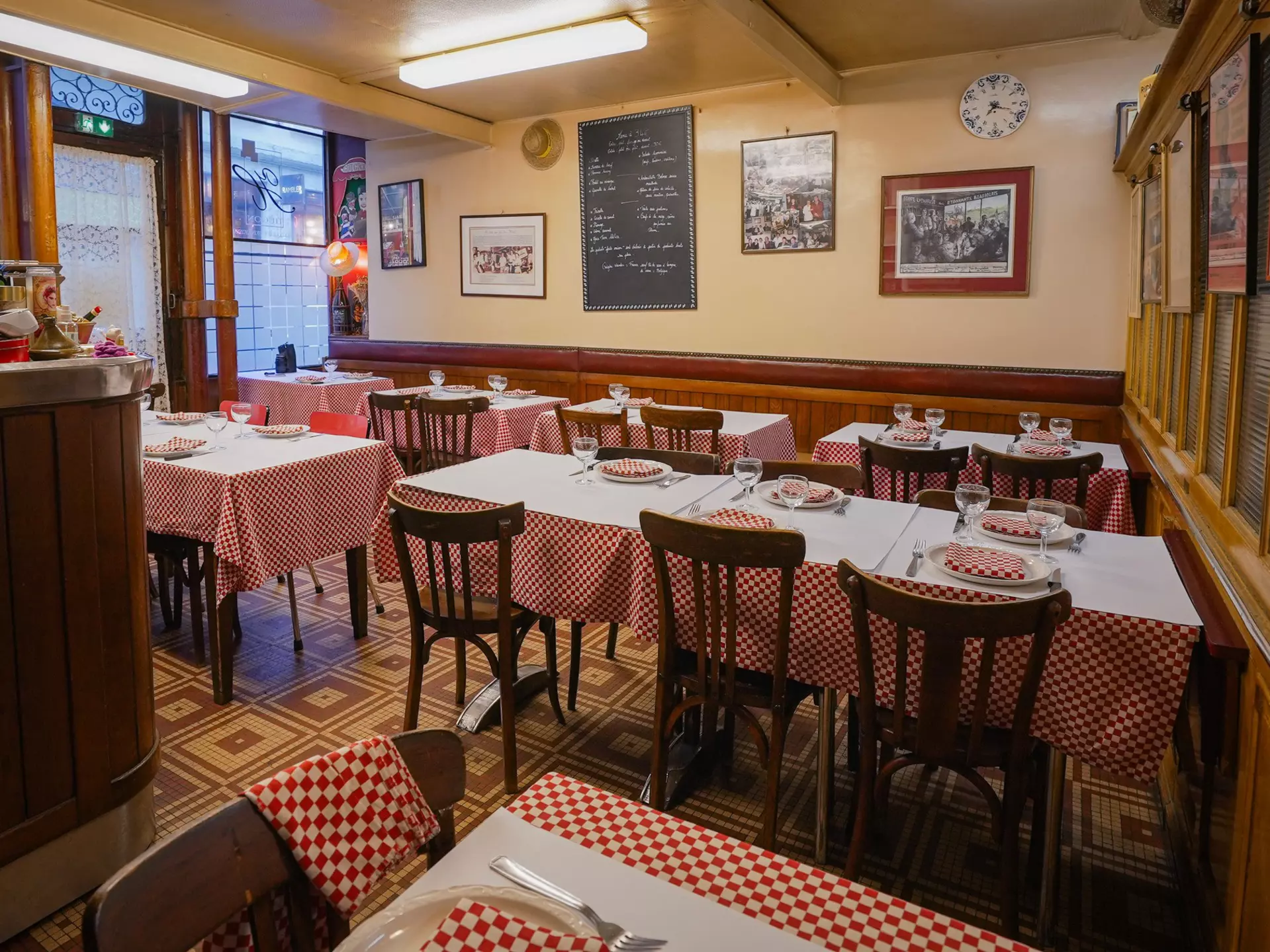 A small bistro with red-and-white checkered table cloths and a menu written in chalk on a blackboard mounted on the wall.