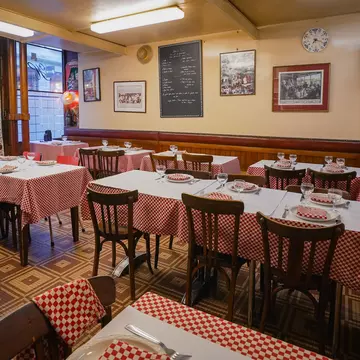 A small bistro with red-and-white checkered table cloths and a menu written in chalk on a blackboard mounted on the wall.