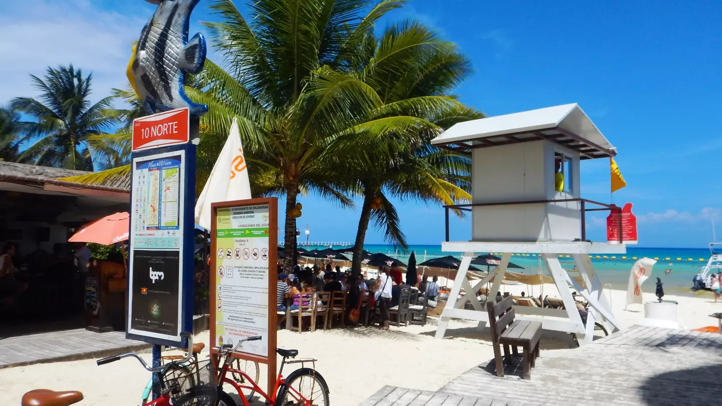 A pair of bicycles parked by a lifeguard station on a boardwalk by the beach in Playa del Carmen, Quintana Roo, Mexico, with the blue Caribbean Sea beyond
