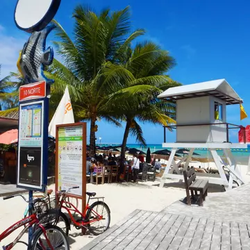 A pair of bicycles parked by a lifeguard station on a boardwalk by the beach in Playa del Carmen, Quintana Roo, Mexico, with the blue Caribbean Sea beyond