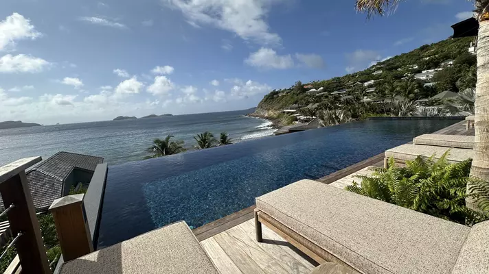 View of an infinity pool and a beach from a villa room
