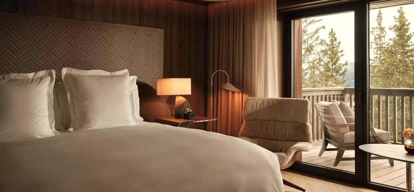 A large bed in a hotel room with a balcony: A deluxe junior suite at Rosewood Courchevel