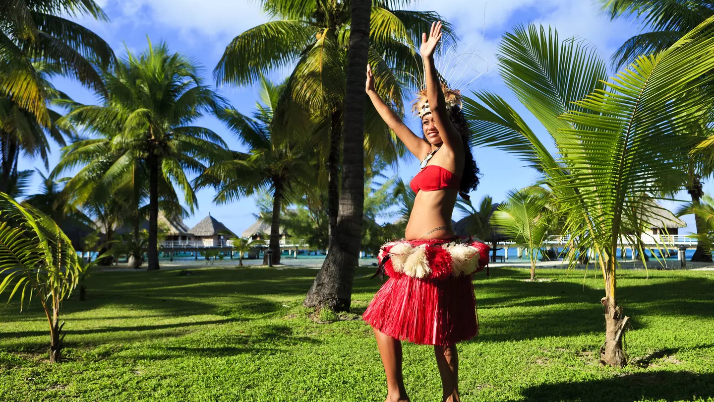 Woman dancing in traditional costume surrounded by palm trees, Bora Bora.
