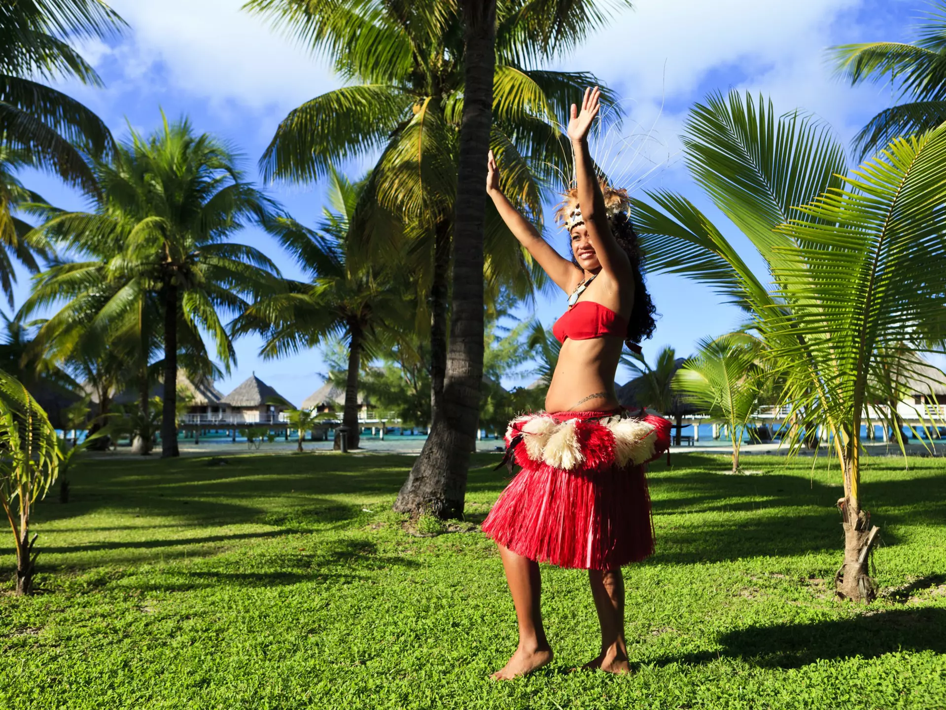 Woman dancing in traditional costume surrounded by palm trees, Bora Bora.