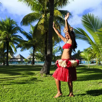 Woman dancing in traditional costume surrounded by palm trees, Bora Bora.