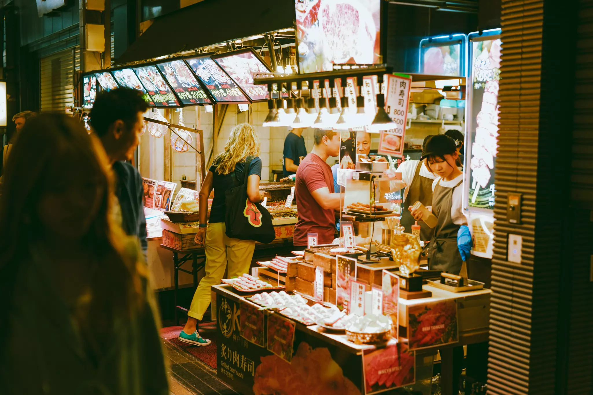 People enter a stall selling food produce in a market environment
