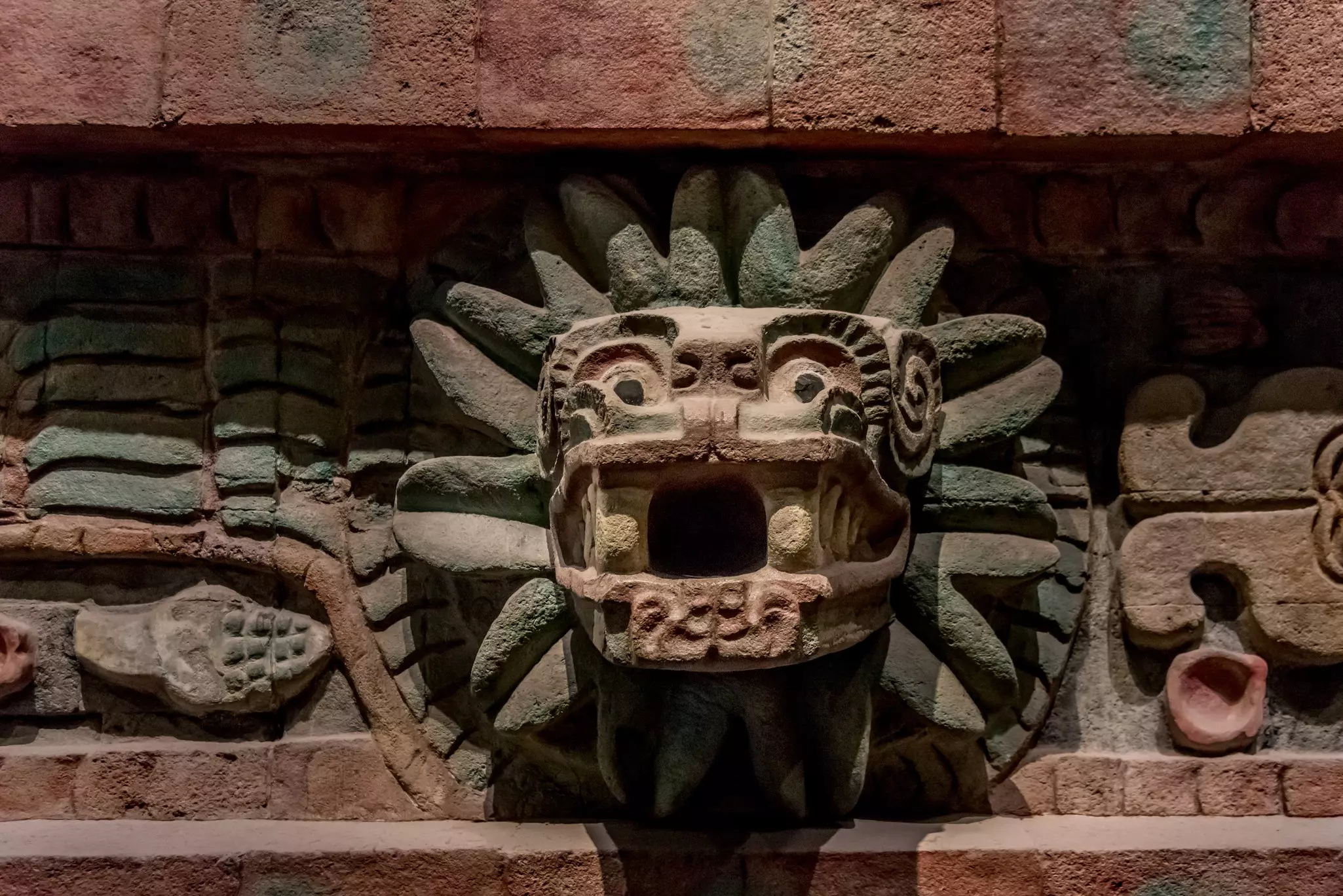 Close-up of a carved serpent head with a spiky mane on the side of a temple at Teotihuacán.