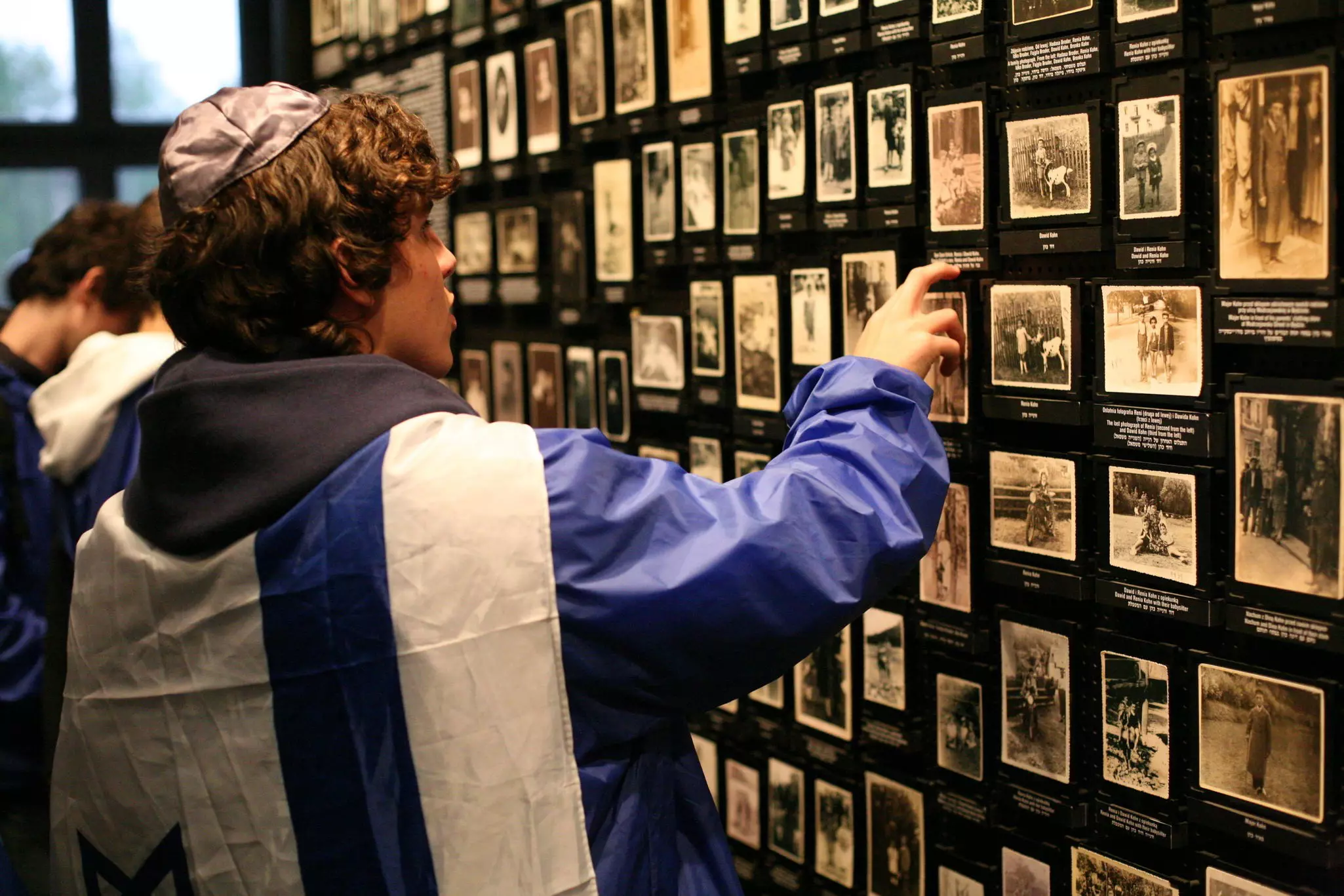 A male visitor wearing a yarmulke points to black-and-white photos at the Auschwitz-Birkenau Memorial and Museum in Poland.