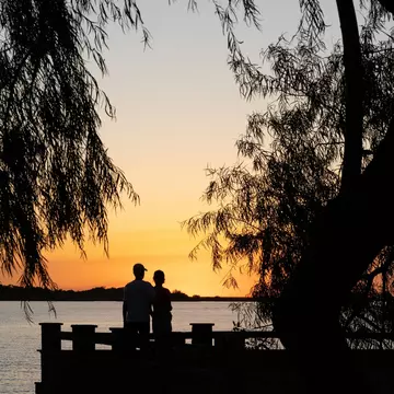 Sunset over wetlands in Conservation Park with egret perched on a wooden boardwalk.