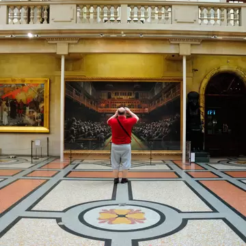 A man takes a picture of an art piece inside the Bristol City Museum & Art Gallery, Bristol, Southwest, England, UK
