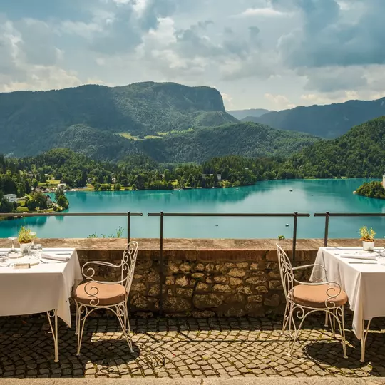 View of outdoor terrace of restaurant overlooking Lake Bled, Slovenia; Alps mountains in background