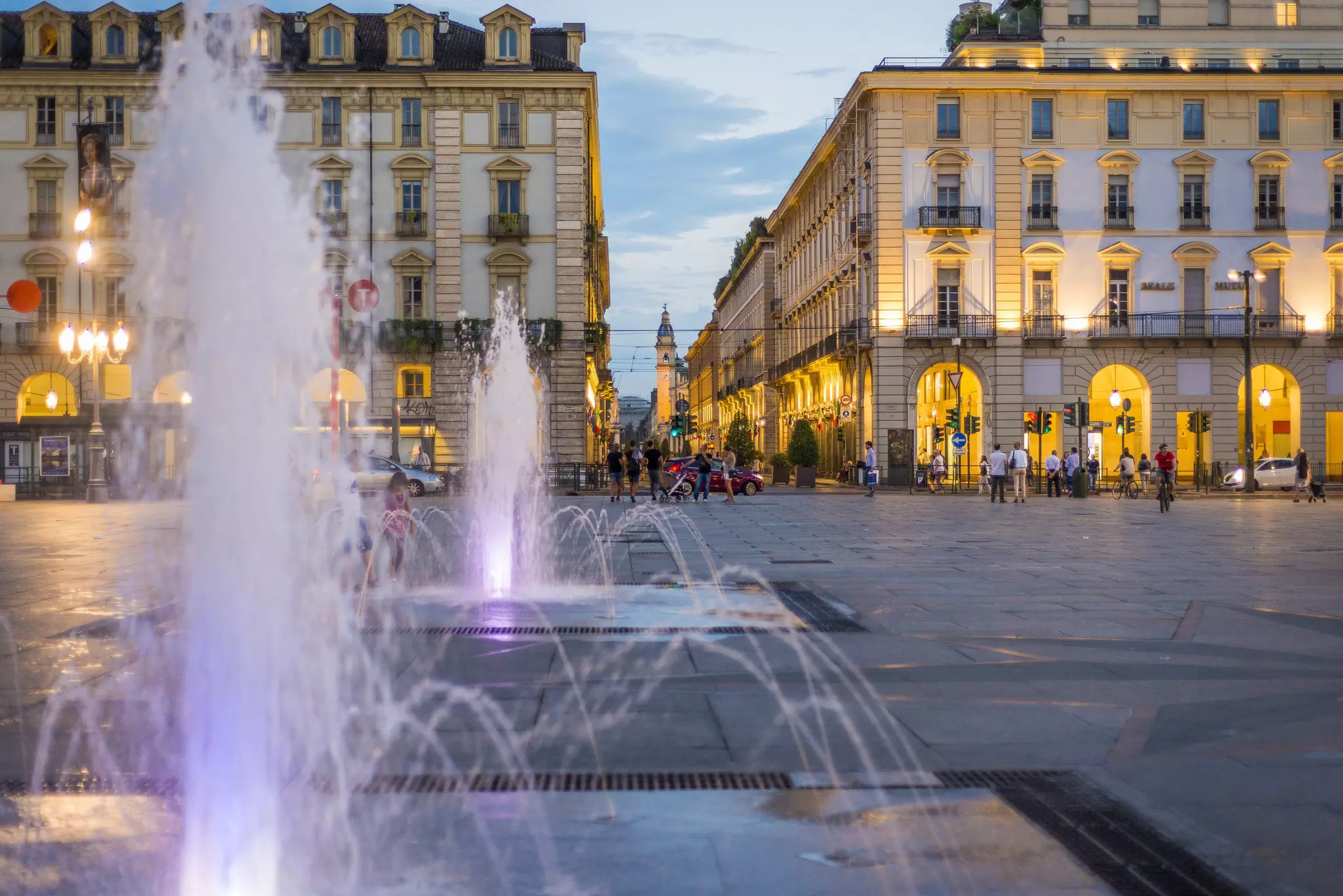 Cyclists, walkers and cars outside the Piazza Castello at night