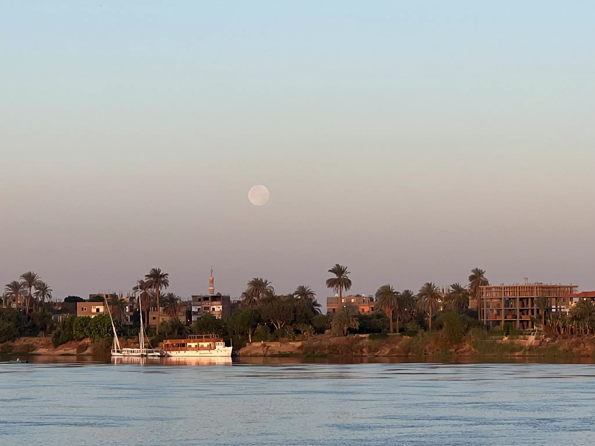 The moon at sunrise on the Nile River in Luxor as seen from aboard a riverboat