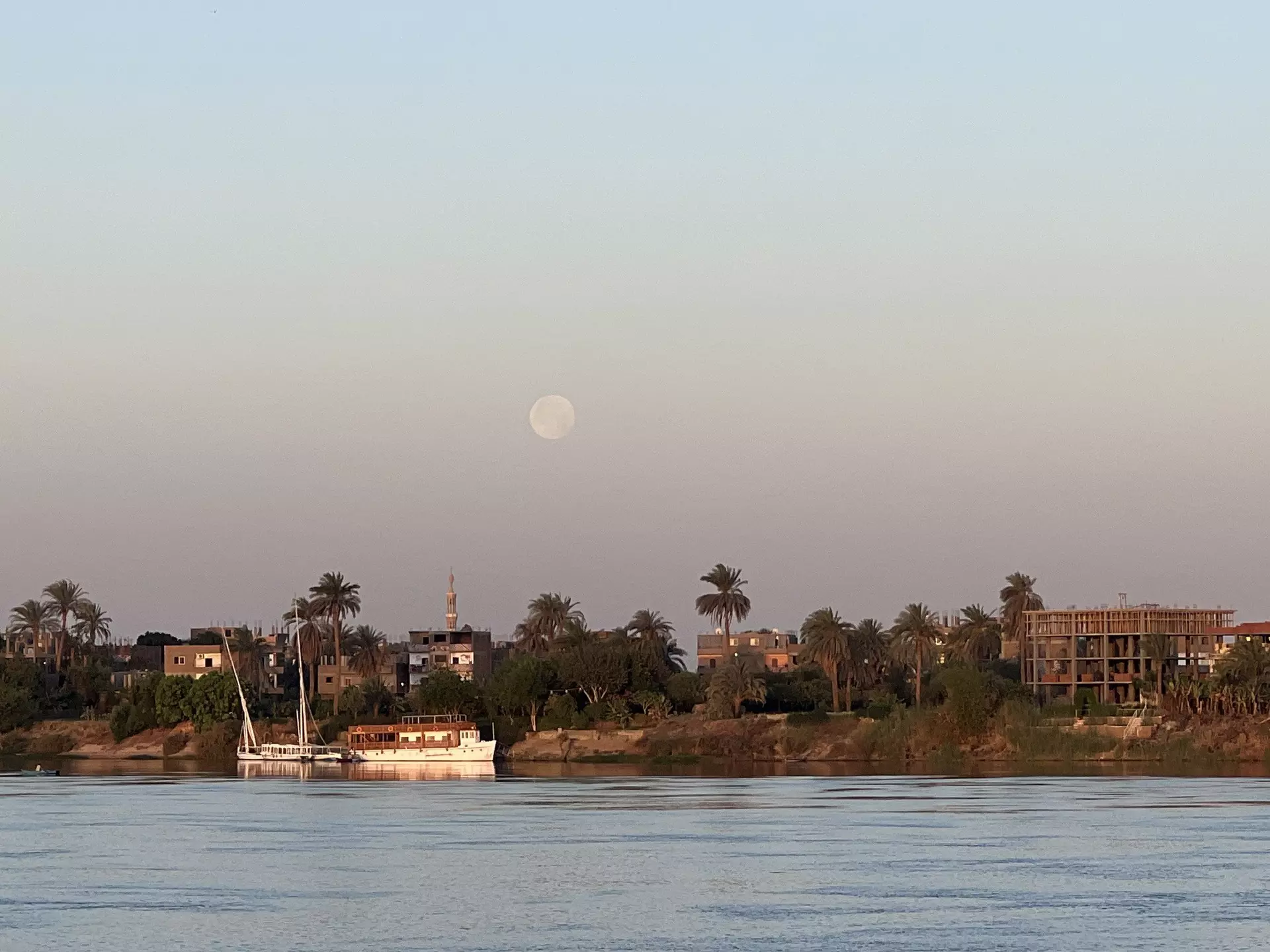 The moon at sunrise on the Nile River in Luxor as seen from aboard a riverboat