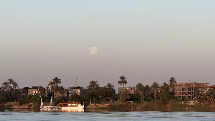 The moon at sunrise on the Nile River in Luxor as seen from aboard a riverboat