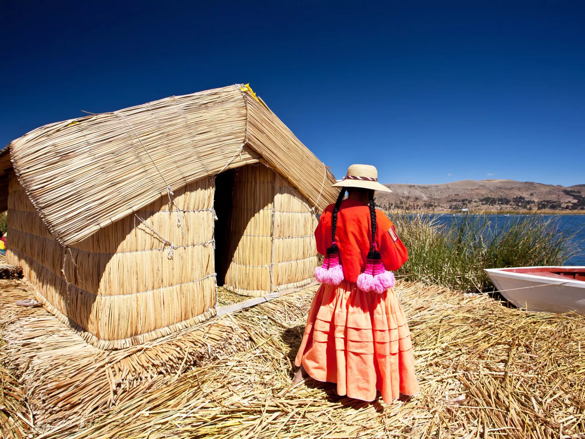 A woman stands outside a reed house on Lake Titikaka, Peru.