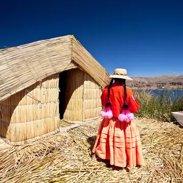 A woman stands outside a reed house on Lake Titikaka, Peru.