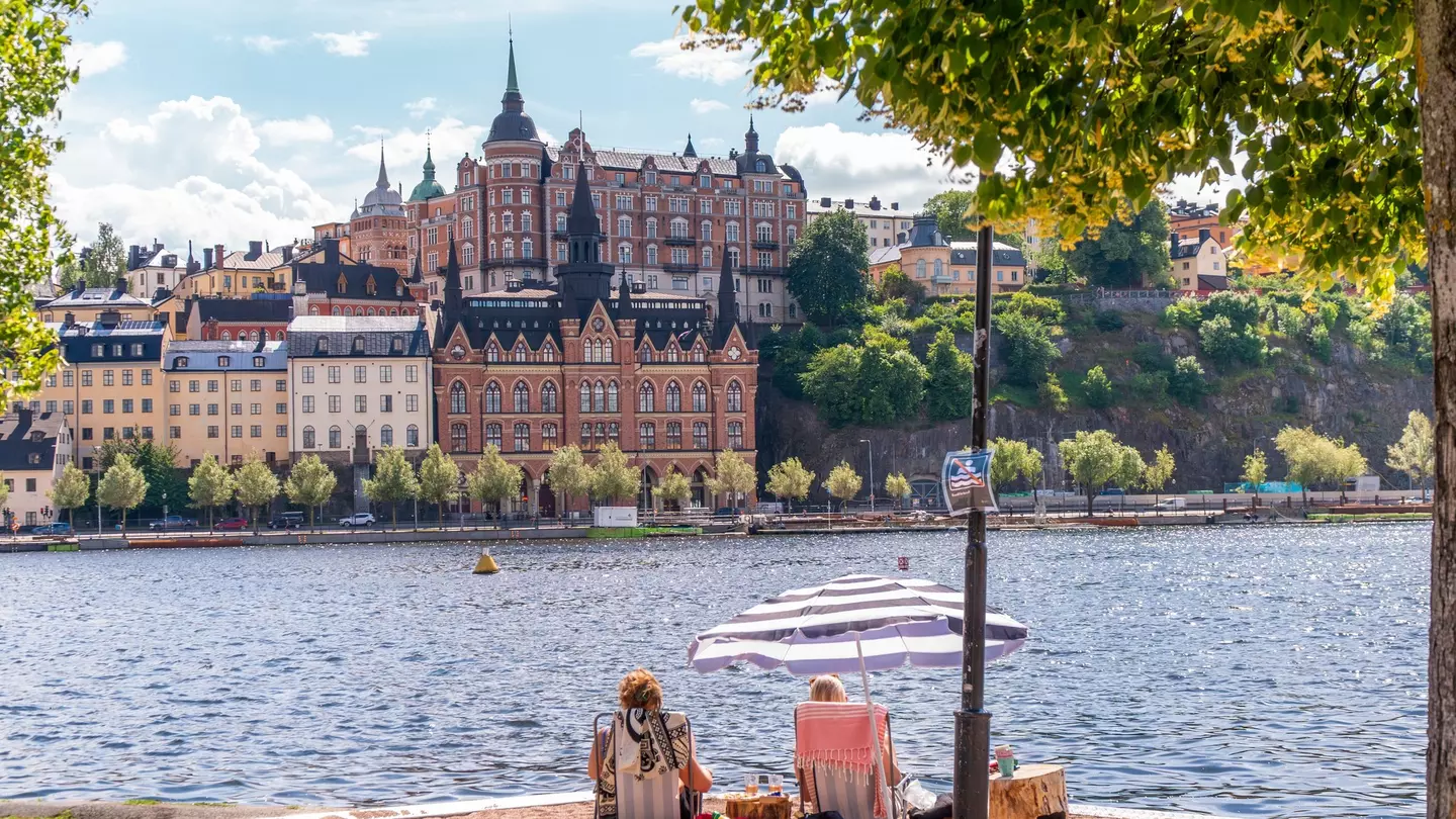 People enjoying the summer sun on a sand bed infront of historical buildings of Södermalm.