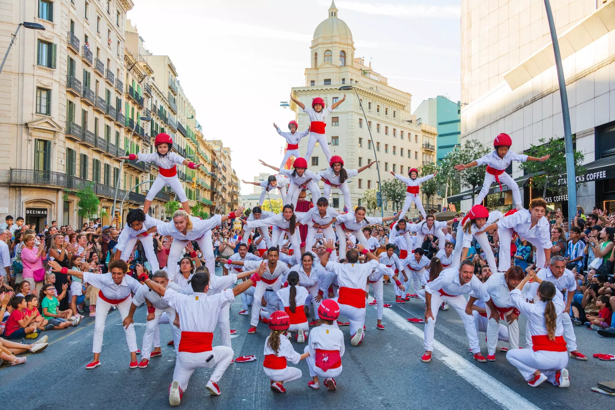 Performers wearing white and red make a human pyramid at a street festival in Barcelona.