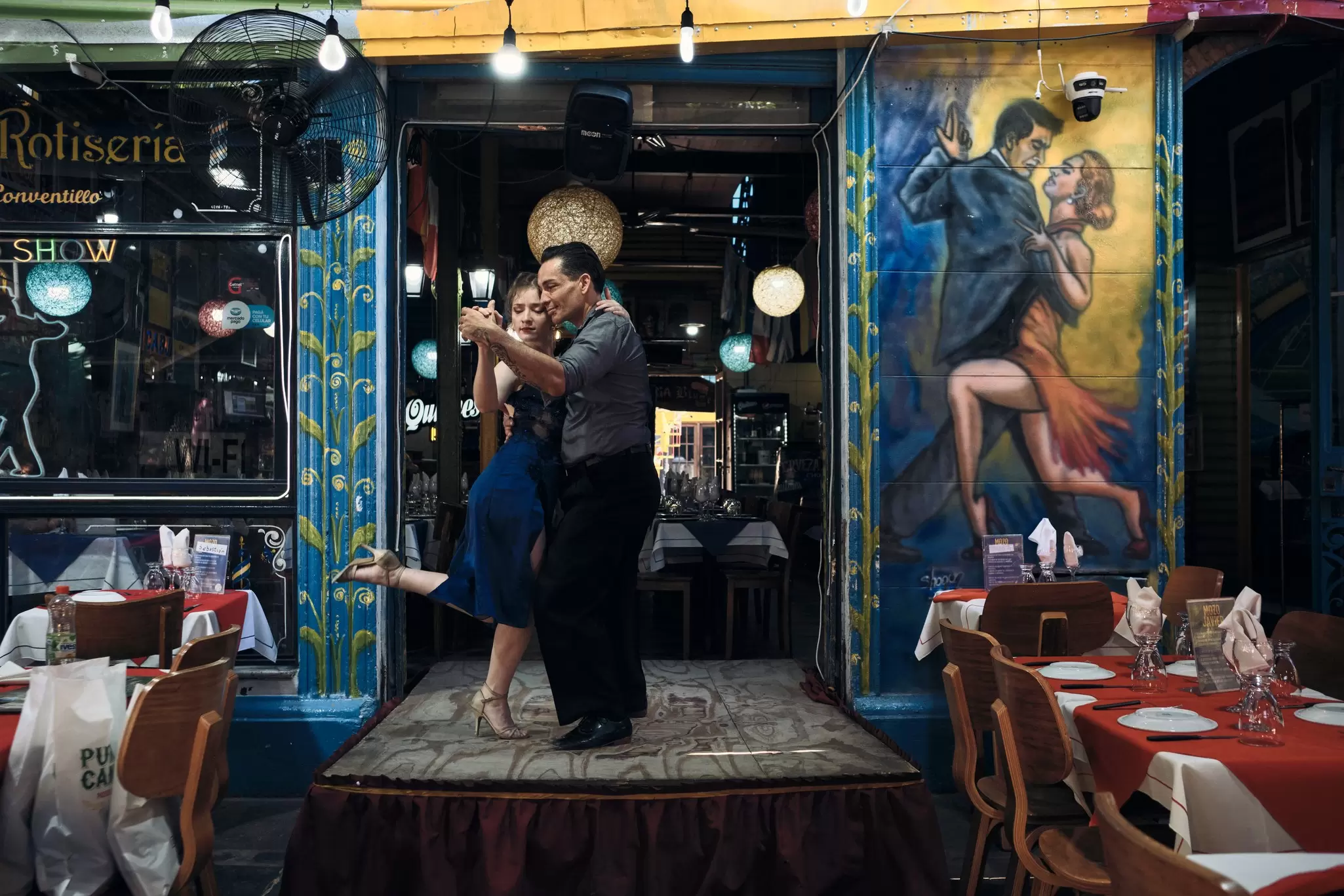 Two dancers performing the tango on a small stage in a restaurant. 