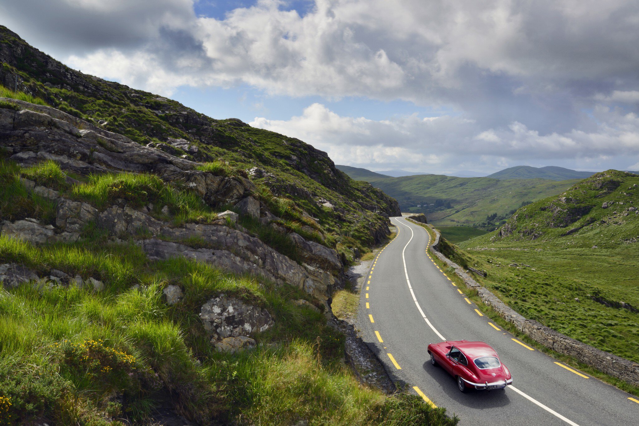 E-Type Jaguar driving on country road between Kenmare and Killarney. County Kerry, Ireland.