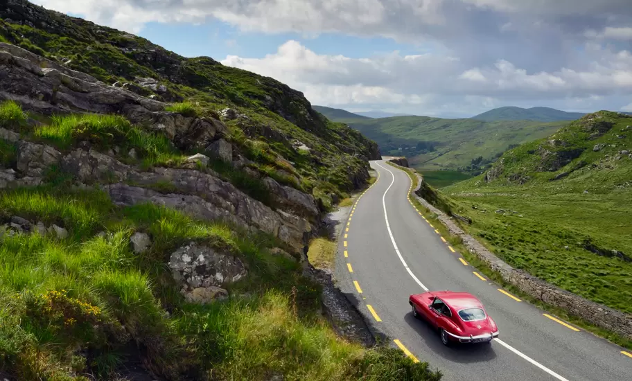 E-Type Jaguar driving on country road between Kenmare and Killarney. County Kerry, Ireland.