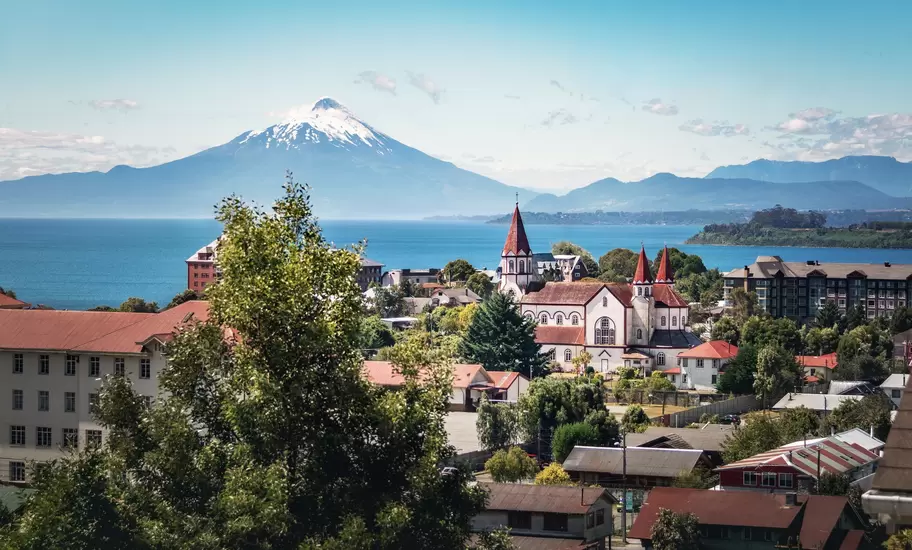 Puerto Varas's red-spired Sagrado Corazón church above rooftops, with Lake Llanquihue and Osorno volcano behind, Chile
