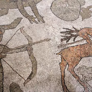 A hunter with a bow and arrow and a stag are depicted in mosaic tiles.