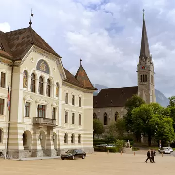 A church with a tall spire in a city square.