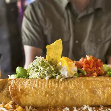 A man sitting at a Mexican food restaurant about to eat a giant chimichanga (fried burrito).
451158965
USA, Food and Drink, Tomato, Mexican Culture, Casual Clothing, L